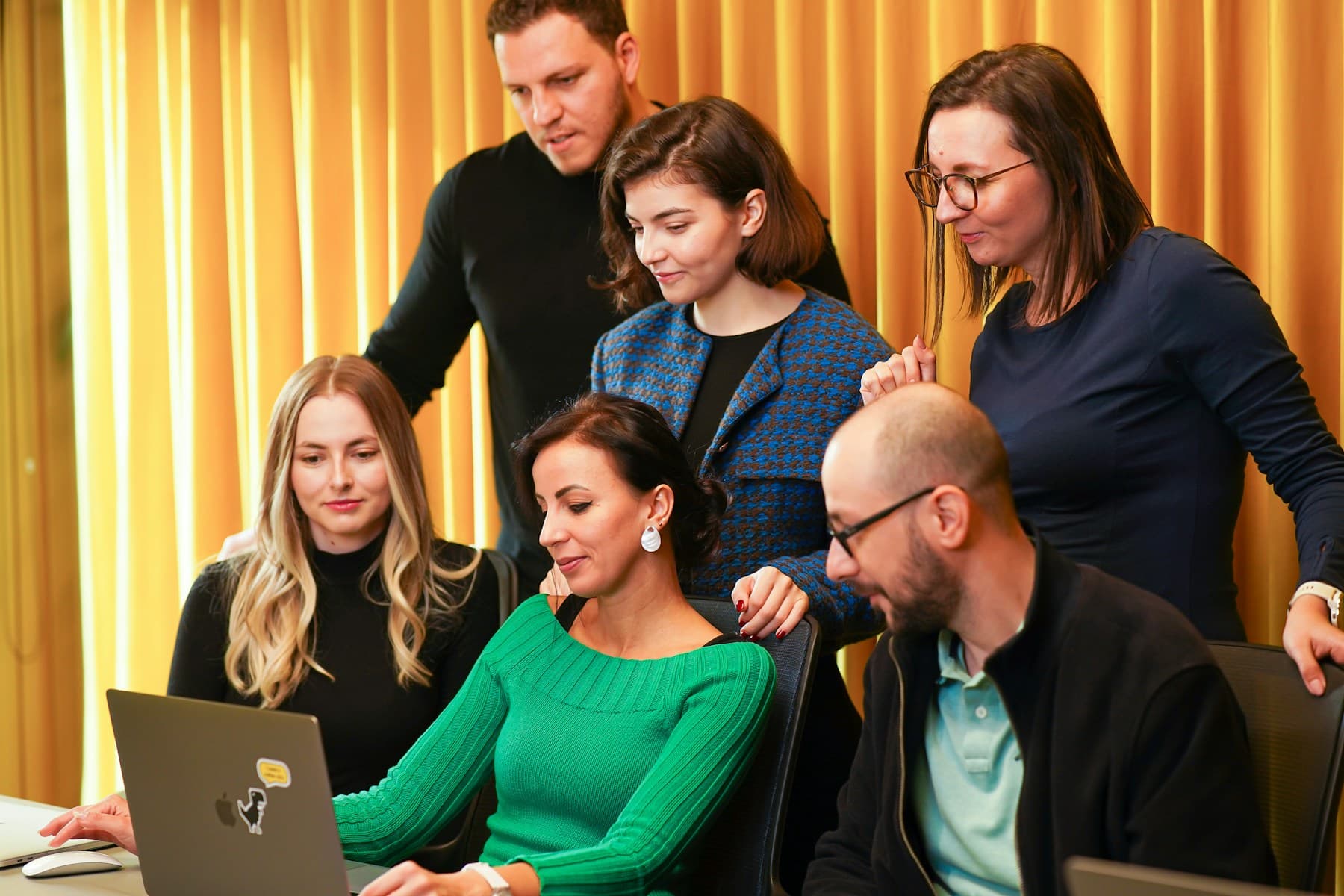 Colleagues reviewing work together around a laptop
